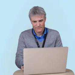 En mann som sitter ved et skrivebord med en bærbar datamaskin