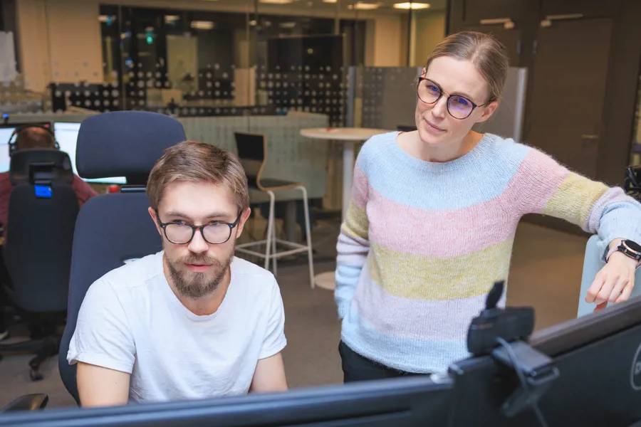 En mann og en kvinne som sitter ved et skrivebord med en datamaskin