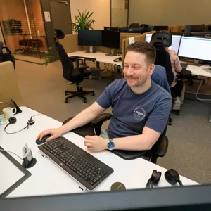 En mann som sitter ved et skrivebord med en datamaskin